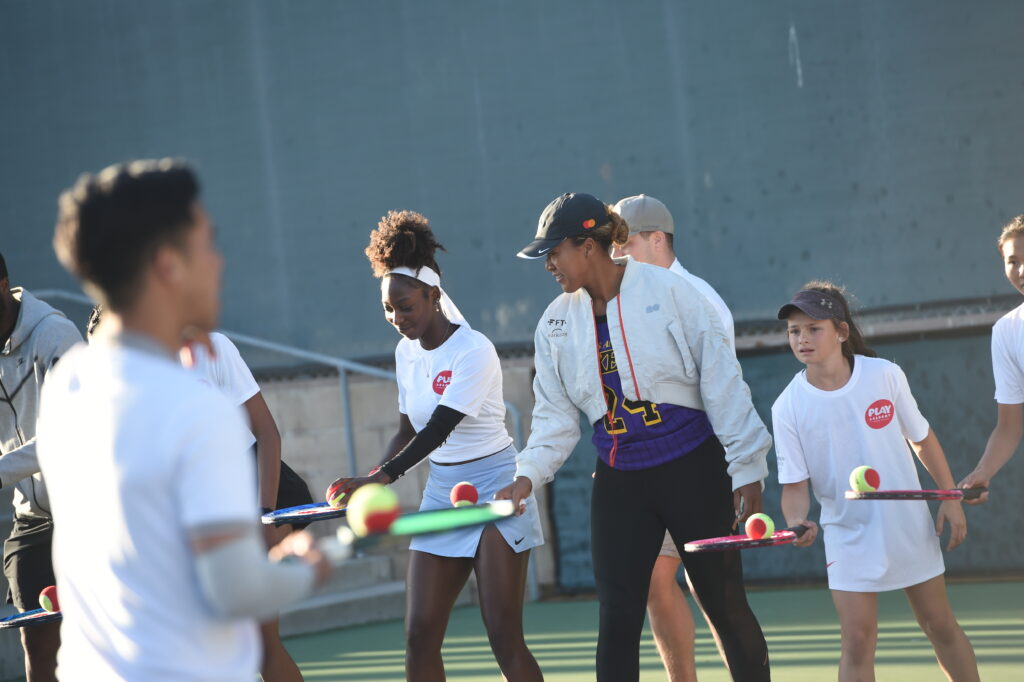 Girls line up balancing tennis ball on racket