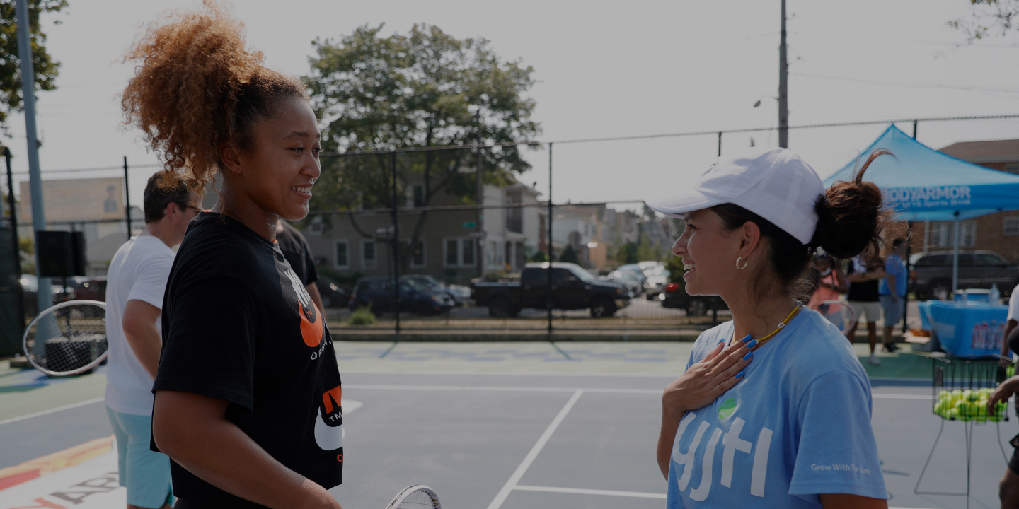 Naomi working with girls on tennis court