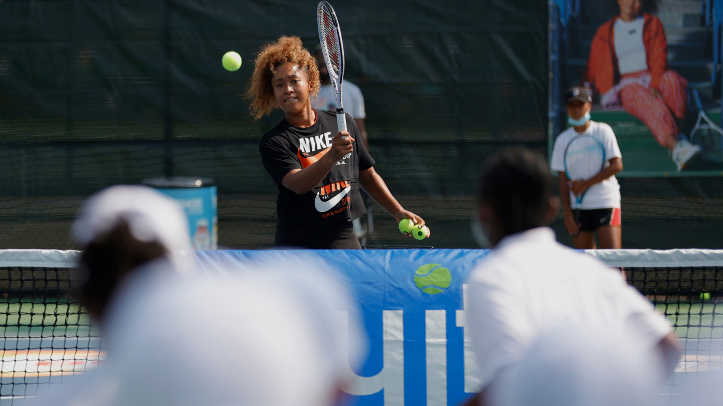 Naomi Osaka serving tennis ball to kids