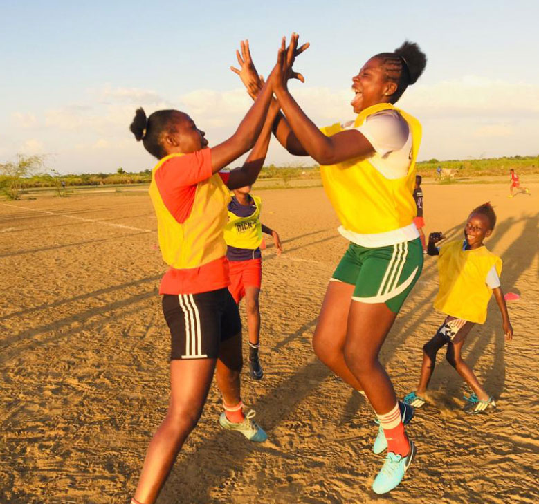 Image of girls in Haiti playing soccer and cheering