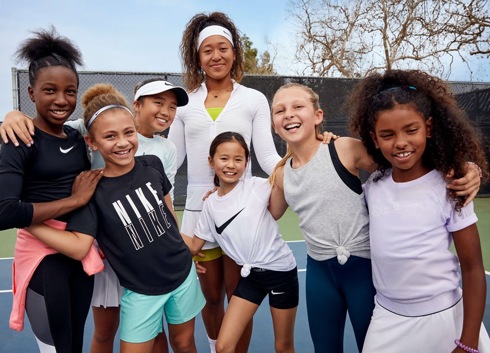 Naomi Osaka posing with girls on a tennis court