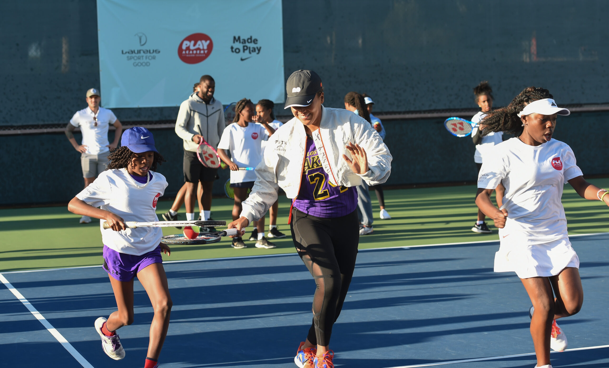Naomi Osaka playing on tennis court with girls