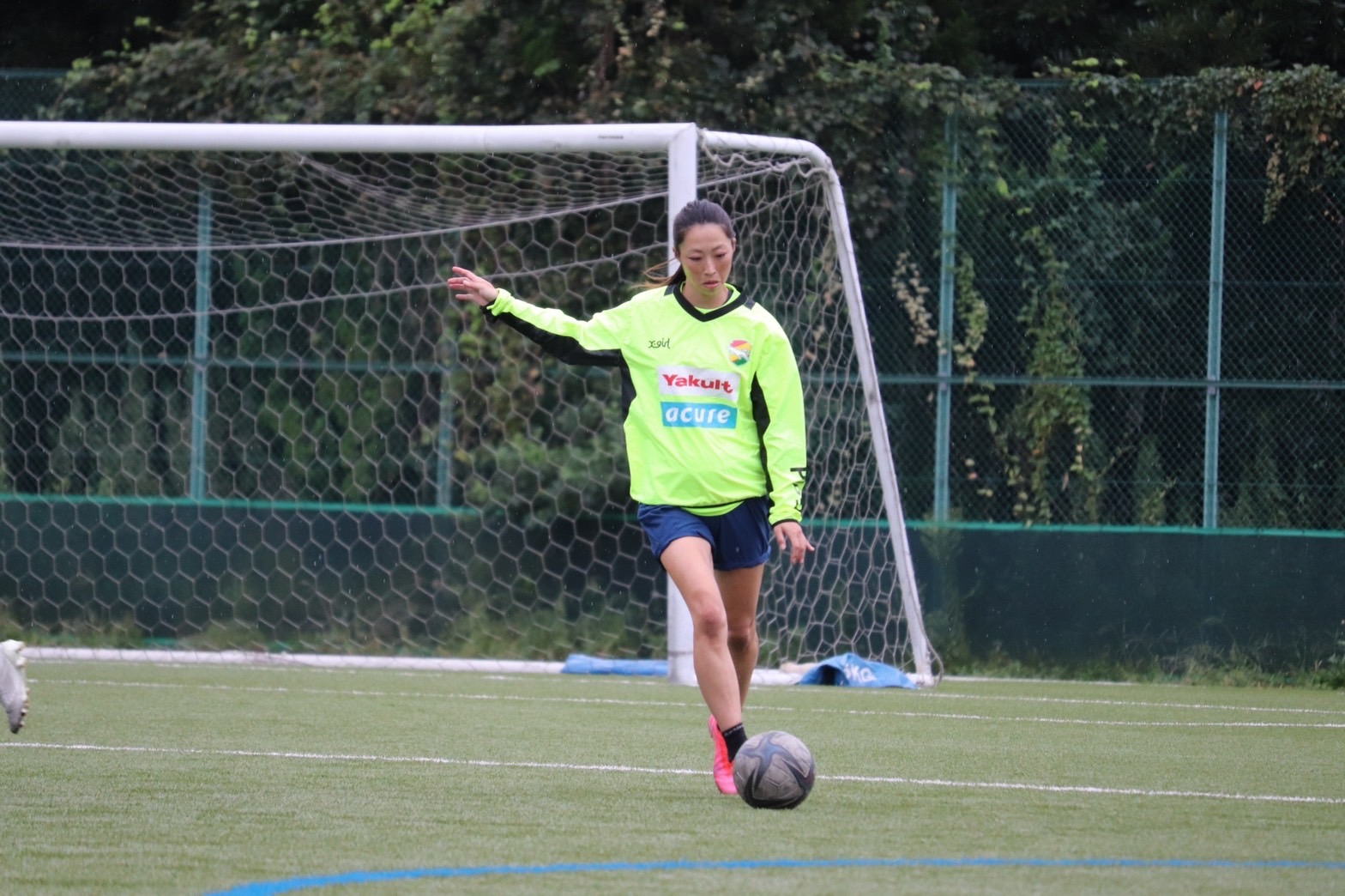 Japanese female soccer player kicks a ball