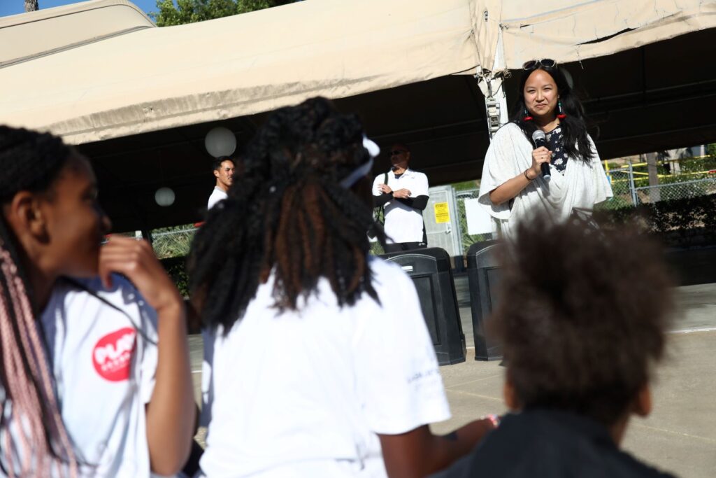 Woman with mic listens to what girls are saying in an activity