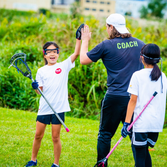 Coach gives participant high five after playing lacrosse