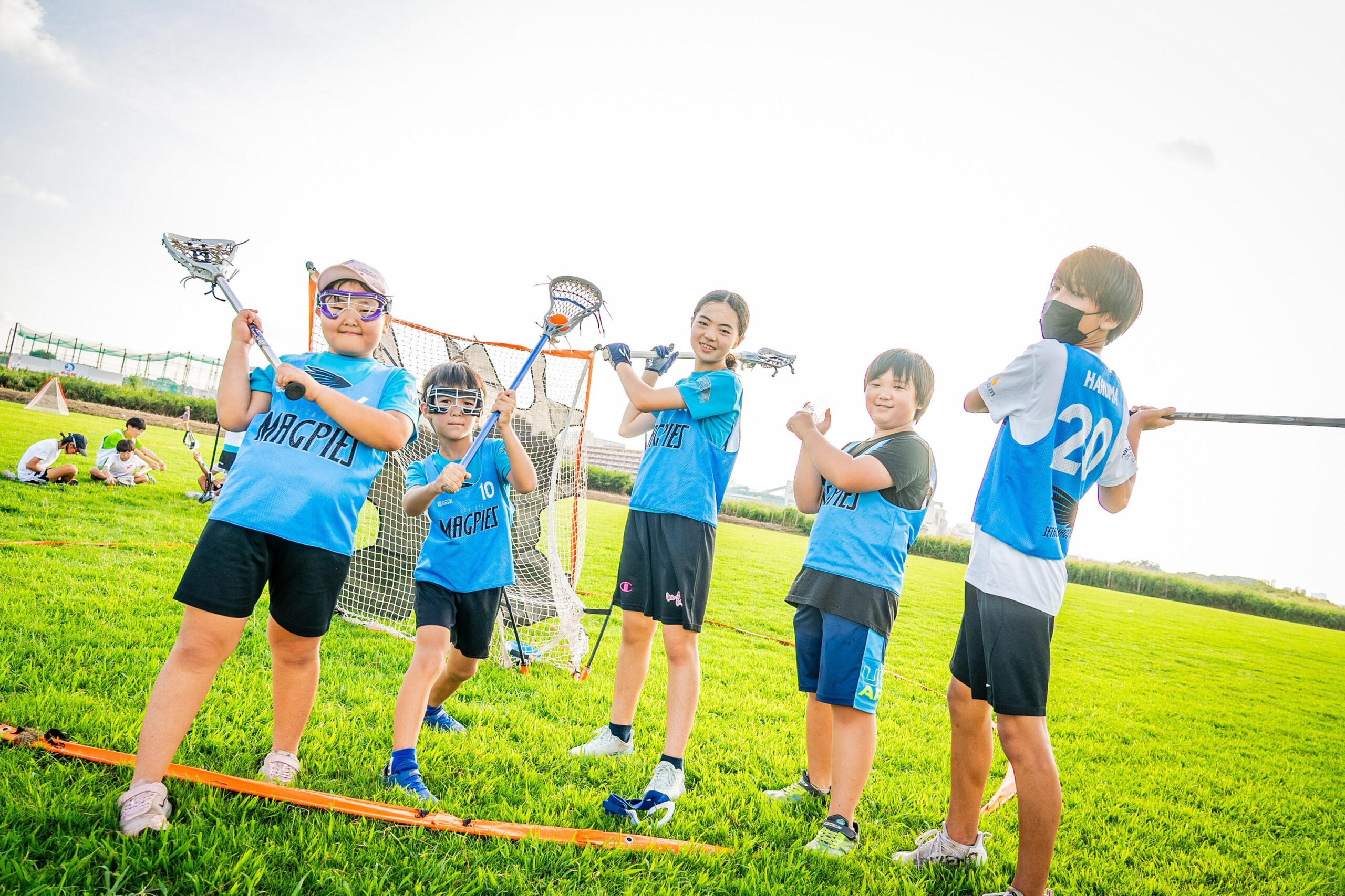 Group of young lacrosse players posing for a photo with their sticks