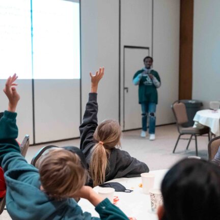 Kids raising their hands as teacher asks a question