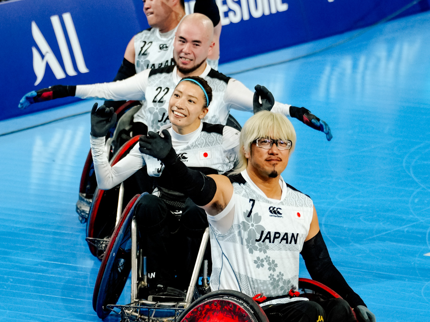 Wheelchair rugby players waving to crowd