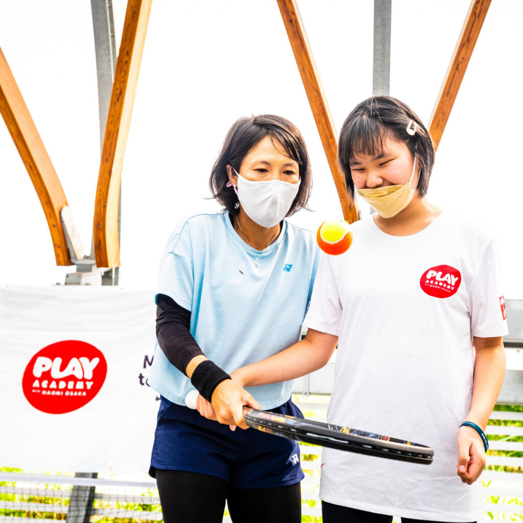 Woman helps girls with tennis racket